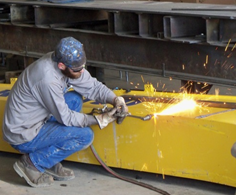 man welding a yellow machine